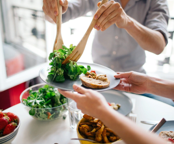 man dressing salad with oil